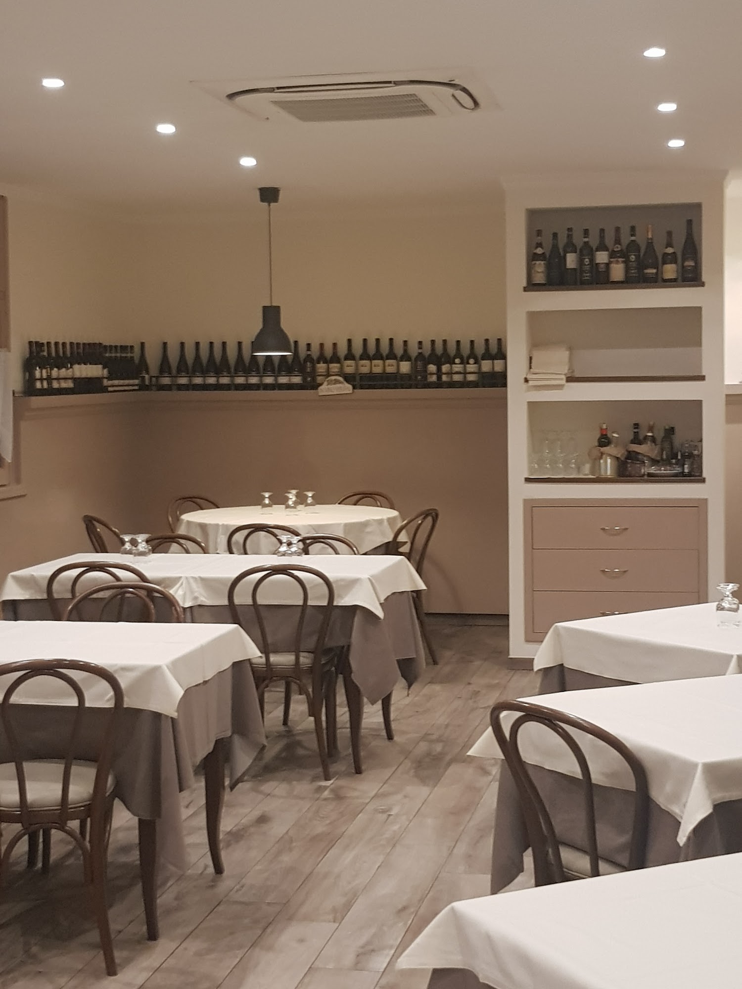 Sala interna della Trattoria Due Archi, tavoli apparecchiati e bottiglie di vino in esposizione